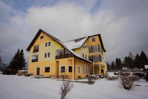 瓦特拉多尔内Pensiunea Valurile Bistritei的屋顶上大黄房子,有雪