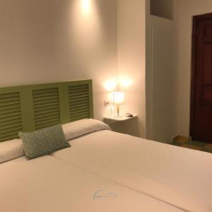 波洛普Hostal León Dormido的一间卧室配有一张白色大床和绿色床头板