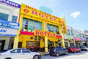 怡保Hill Times Inn Hotel的黄色的酒店,前面有车辆停放