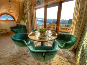 亚沃尔基Dziejba Leśna Apartamenty &Spa的配有大窗户的客房内的桌椅