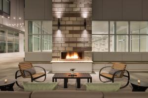 罗切斯特EVEN Hotels Rochester - Mayo Clinic Area, an IHG Hotel的大堂的壁炉,配有椅子和桌子