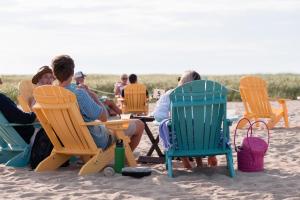 丹尼斯Bluebird Dennisport的一群人坐在海滩上的草坪椅上