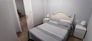 马拉加APARTAMENTO HUERTA NUEVA的一间白色的小卧室,配有床和2个床头柜