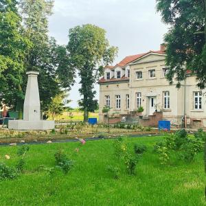 戈斯滕Palac Osowo gostynskie的前面草上有纪念碑的房子