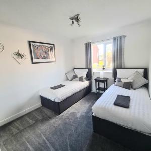 巴洛赫Levenside Holiday Apartment, Balloch, Loch Lomond的酒店客房设有两张床和窗户。