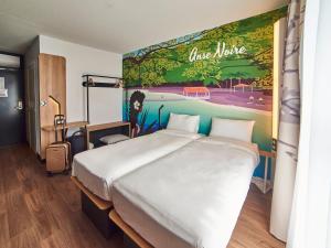 法兰西堡B&B HOTEL Fort-de-France的卧室配有一张大床,墙上挂有绘画作品