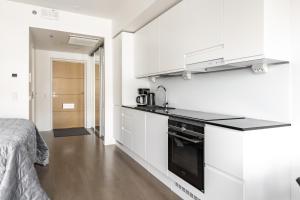 坦佩雷Brand-new City Home 2的一间厨房,配有白色的橱柜和一张位于客房内的床