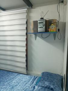 圣地亚哥Terminal Pajarito的一间卧室配有一张床,架子上配有微波炉