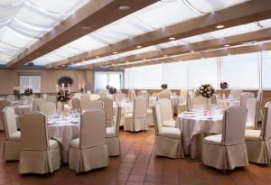 那不勒斯特米努斯星际酒店的宴会厅配有白色的桌子和白色的椅子
