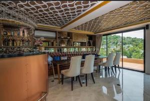 他朗Phuket apartment surin beach的一间用餐室,内设带白色椅子的酒吧