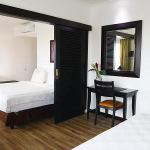 当格浪Jakarta Airport Hotel的一间卧室配有一张床、一张书桌和一面镜子