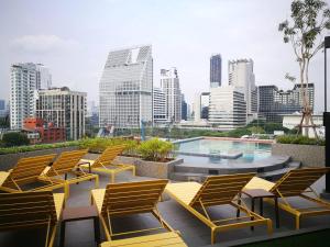 曼谷The Quart Ruamrudee by UHG - Extra Plus的一组椅子和一个游泳池位于一座大楼内