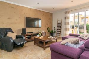马拉特克西Joan Deia Escultor的客厅配有两张紫色沙发和一台电视机