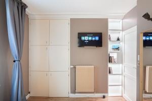 尚蒂伊Suite Appart Place Versepuy的一间设有白色橱柜和墙上电视的房间