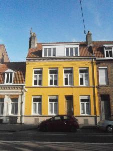 敦刻尔克布鲁尼瓦尔酒店的一座黄色的房子,前面有一辆汽车