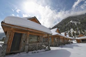 SaturangOsiya Rangnoo Rakchham Retreat的雪地小木屋,有雪盖屋顶