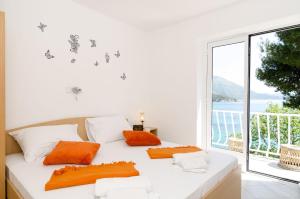 米利尼丹妮拉旅馆的窗户客房内的白色床和橙色枕头