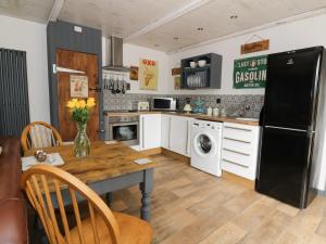 霍舍姆圣斐德Foxley Wood Cottage的厨房配有桌子和黑冰箱。
