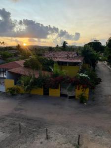 圣若泽-达科罗阿格兰迪Village do Sossego的黄色房子,背景是日落