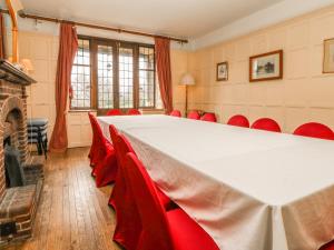ChiddingstoneHoath House的一间会议室,配有大桌子和红色椅子