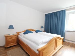 塞费尔德附近赖特Apartment Isolde by Interhome的一间卧室配有一张带蓝色窗帘的木床和窗户。