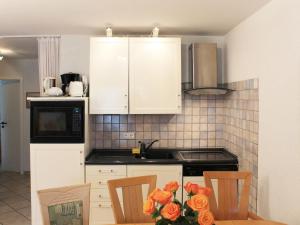 高尔维茨Apartment Gollwitzer Park - Insel Poel-10 by Interhome的厨房配有白色橱柜和鲜花桌