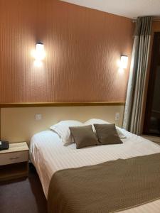 勒马尔奇奥·维勒Logis Hotel Restaurant des Voyageurs的一间卧室配有一张大床和两个枕头