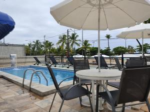 马塞约海湾海滩酒店的游泳池旁配有遮阳伞的桌椅