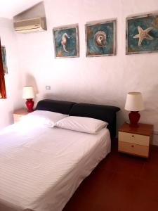 切尔沃港L'Olivastro的一间卧室配有一张带两盏灯的床,墙上挂有绘画作品