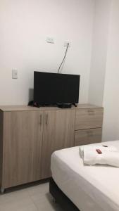 CamaronesOMA HOTEL LA GUAJIRA的卧室配有木柜上的平面电视