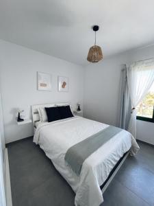 科斯塔特吉塞Apartamentos Cataira的白色的卧室设有一张大床和一个窗户