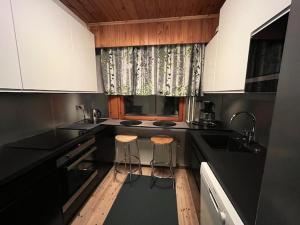 TikkakoskiHuoneisto Tikkakoski - Apartment in Tikkakoski的厨房配有黑色柜台和两张凳子