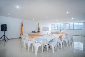 伊瓦格Ayenda Gold Plaza的用餐室配有白色的桌子和白色的椅子
