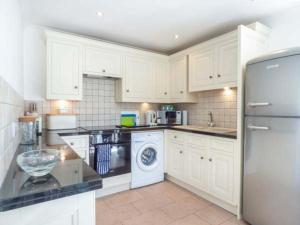 圣梅尔林7 Harlyn Cottages的厨房配有白色橱柜、洗衣机和烘干机