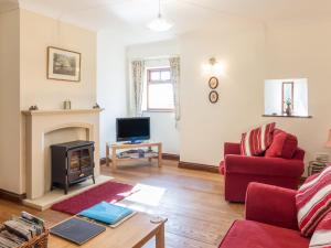 LongwittonRidge Cottage的客厅设有壁炉和红色沙发。