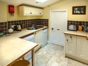 斯泰兹Broomhill View的厨房配有白色橱柜、水槽和门