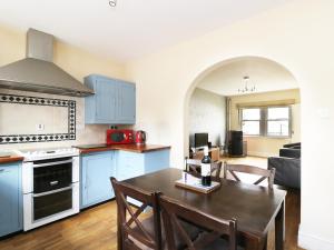 Santon BridgeWilliam Court Cottage的厨房配有蓝色橱柜和桌椅