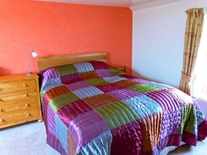 Great UrswickThe Crook的一间卧室配有一张色彩缤纷的床和木制梳妆台。