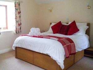 WortleyHollins Wood Bothy的卧室配有一张带白色和红色枕头的大床