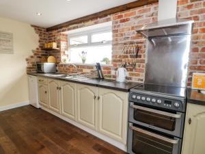 LlangyninFfynnonlwyd Cottage的厨房配有白色橱柜和砖墙