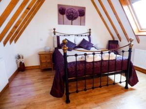 DunningtonThe Barn Ivy Cottage的一间卧室配有一张黑色床和紫色枕头