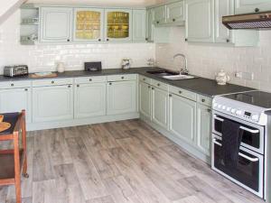 惠特彻奇Ganarew Cottage的厨房铺有木地板,配有白色橱柜。