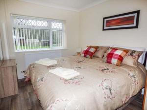 LlanharanCwm Gran Meadows的卧室配有带枕头的大床和窗户。