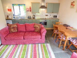 温福德The Old Parlour的客厅设有粉红色沙发,厨房设有