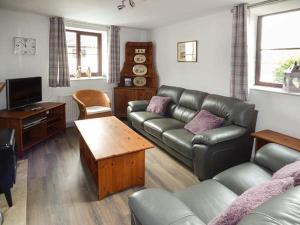 金斯坦顿Fairwater Mill Cottage的客厅配有真皮沙发和电视