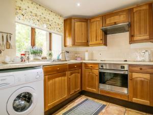 MorlandRosegarth Cottage的厨房配有木制橱柜、洗衣机和烘干机