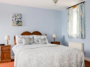 MorlandRosegarth Cottage的一间卧室配有一张带蓝色墙壁的大床
