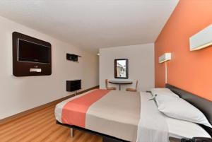 沃思堡沃思堡6号汽车旅馆 - 东城的卧室配有一张床,墙上配有电视。