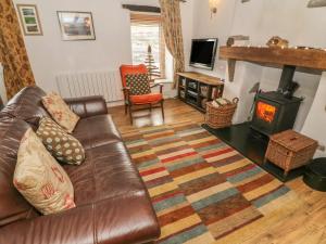 康福斯Rosemary Cottage的客厅配有真皮沙发和木柴炉。