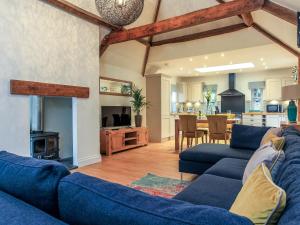 奇彭纳姆Woodmans Cottage Nables Farm的一间带2张蓝色沙发的客厅和一间厨房